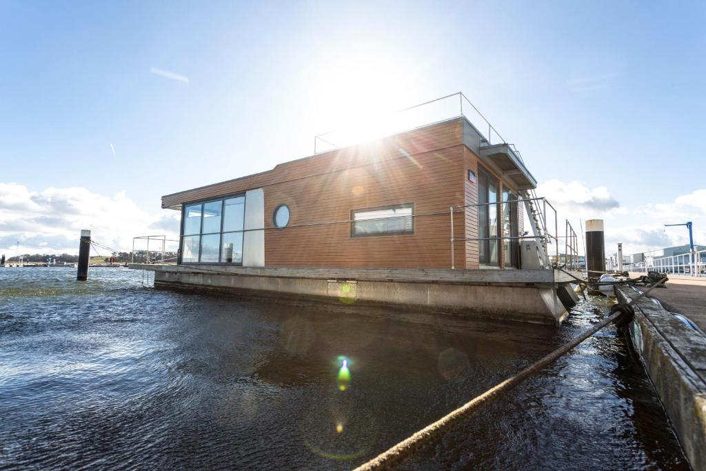 a house on a body of water with the sun shining on it at Hausboot Tollow in Kröslin