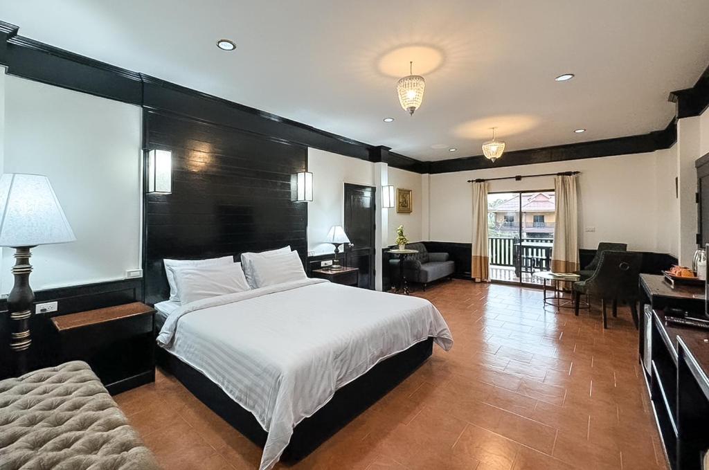 a bedroom with a large bed and a living room at Silamanee Resort & Spa Hotel in Mae Sai