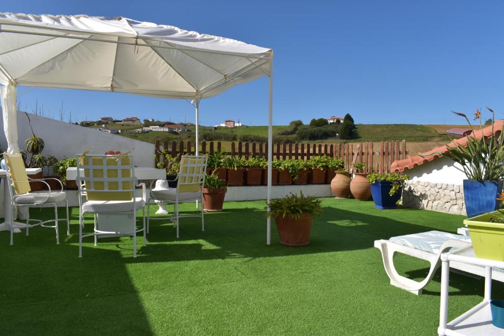 a table and chairs under a white umbrella at Casa Belo Horizonte in Lourinhã