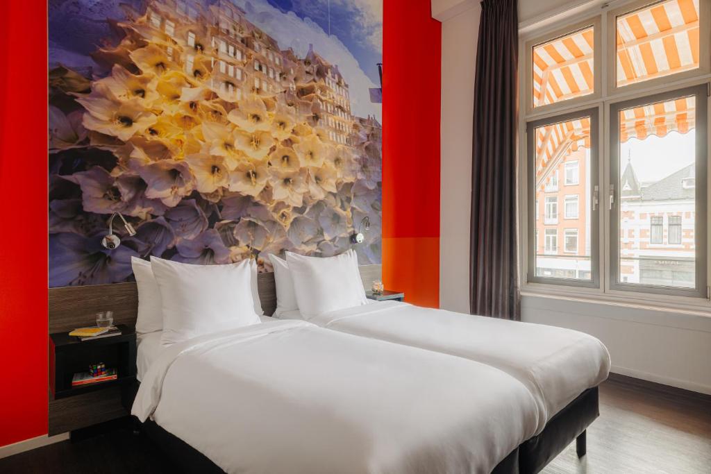 twee bedden in een kamer met een schilderij aan de muur bij The Manor Amsterdam in Amsterdam