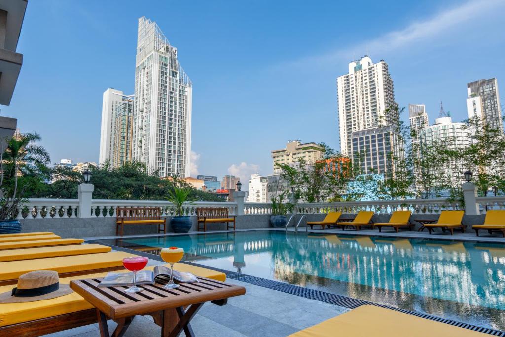 einen Pool mit Tischen, Stühlen und Gebäuden in der Unterkunft Boulevard Hotel Bangkok Sukhumvit in Bangkok
