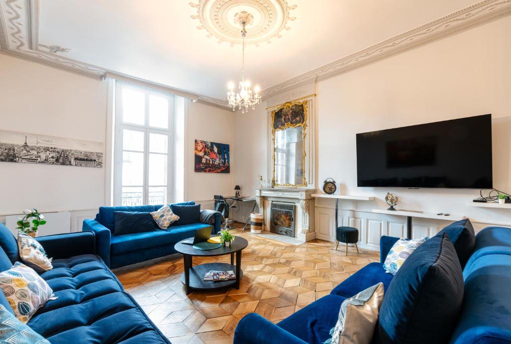 ein Wohnzimmer mit blauen Sofas und einem TV in der Unterkunft Appartement immeuble le bringer 180m2 in Marvejols