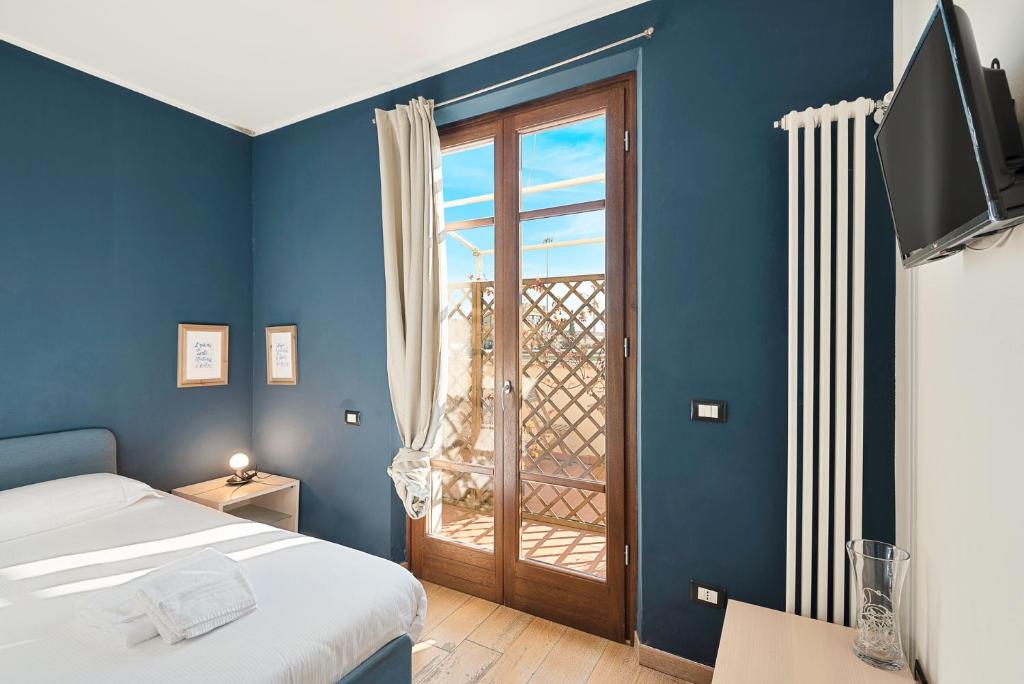 Dormitorio azul con cama y ventana en Accogliente camera singola con balcone a 500 mt dal mare en Marina di Carrara