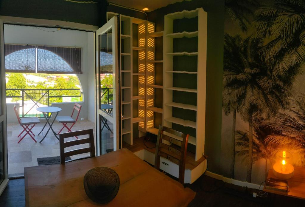 a dining room with a table and chairs and a balcony at Les Fauvettes in Saint-Paul