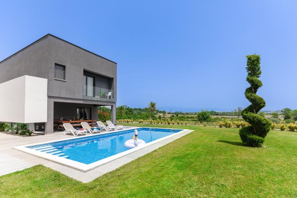 a villa with a swimming pool in front of a house at Villa Lux ZadarVillas in Zemuniki