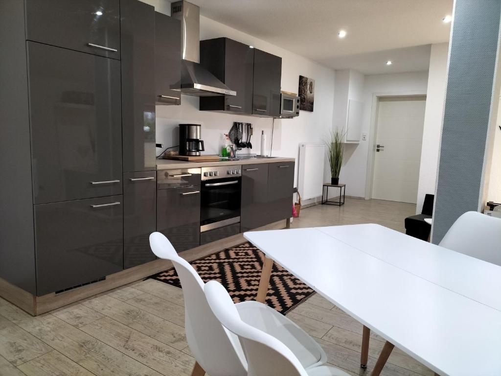 a kitchen with a white table and white chairs at Ferienwohnung Auszeit 65354 in Moormerland