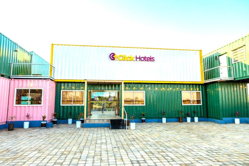 MundraClick Hotel Mundra的粉红色和绿色建筑前的商店
