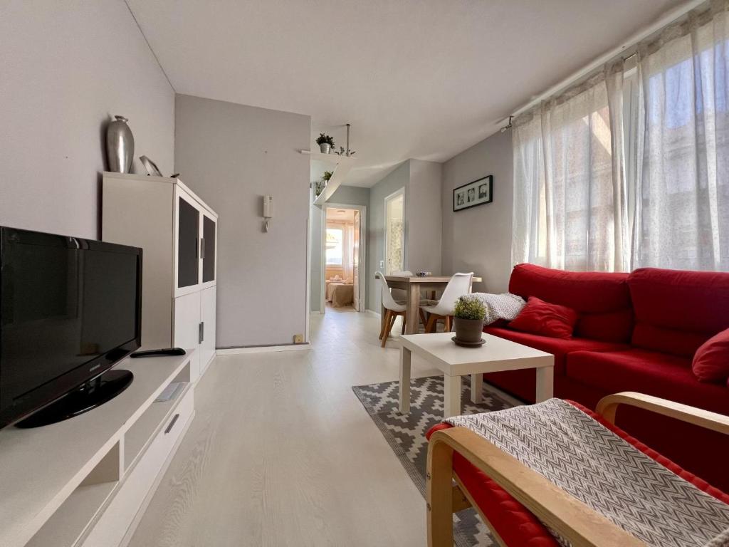 a living room with a red couch and a tv at Apartamento Somo Puerto in Somo