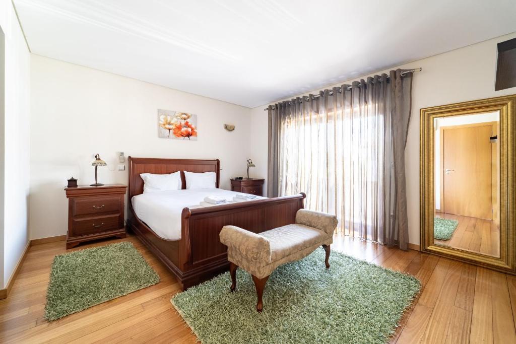 a bedroom with a bed and a chair and a mirror at Casa de Palmeira by House and People in Burgueiros