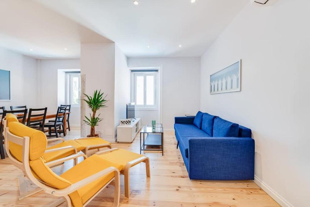 ein Wohnzimmer mit einem blauen Sofa und Stühlen in der Unterkunft Cozy Coastal Getaway 3BR Apartment in Estoril in Estoril