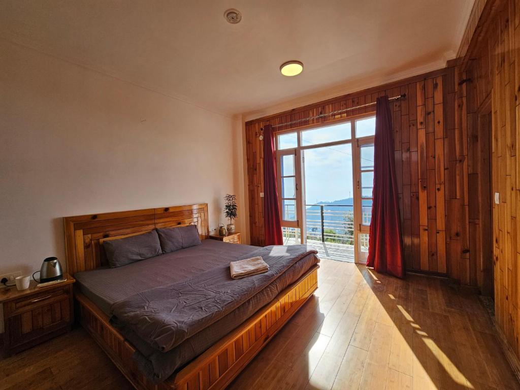 a bedroom with a bed and a large window at Young Monk Hostel & Cafe Dharamkot in McLeod Ganj