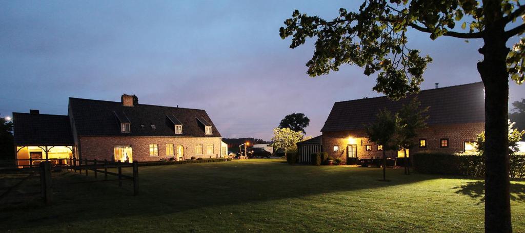 a couple of buildings with a grass yard at night at De Peirdestal in Pittem