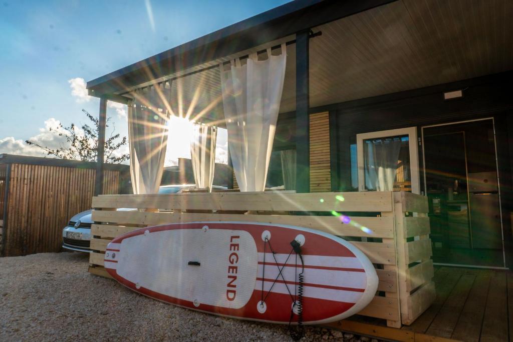 a surfboard sitting in front of a house at The Sol Home - Mobile Home in Drage, Pakoštane in Pakoštane