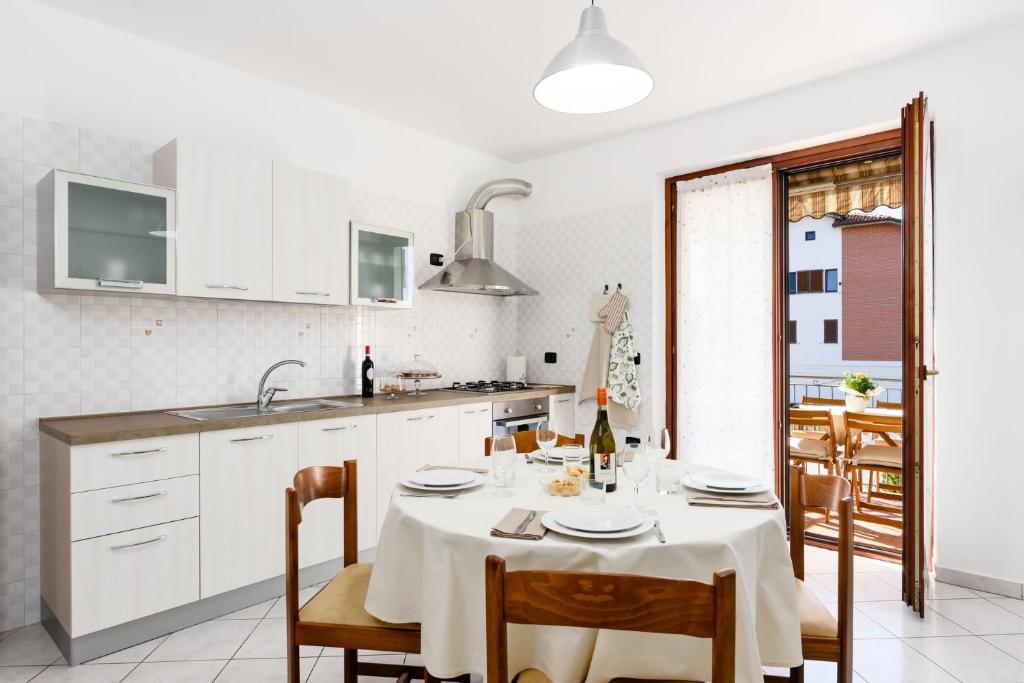 una cocina con mesa y sillas y una cocina con armarios blancos. en Casa Dany - Alba - Family Apartment, en Guarene