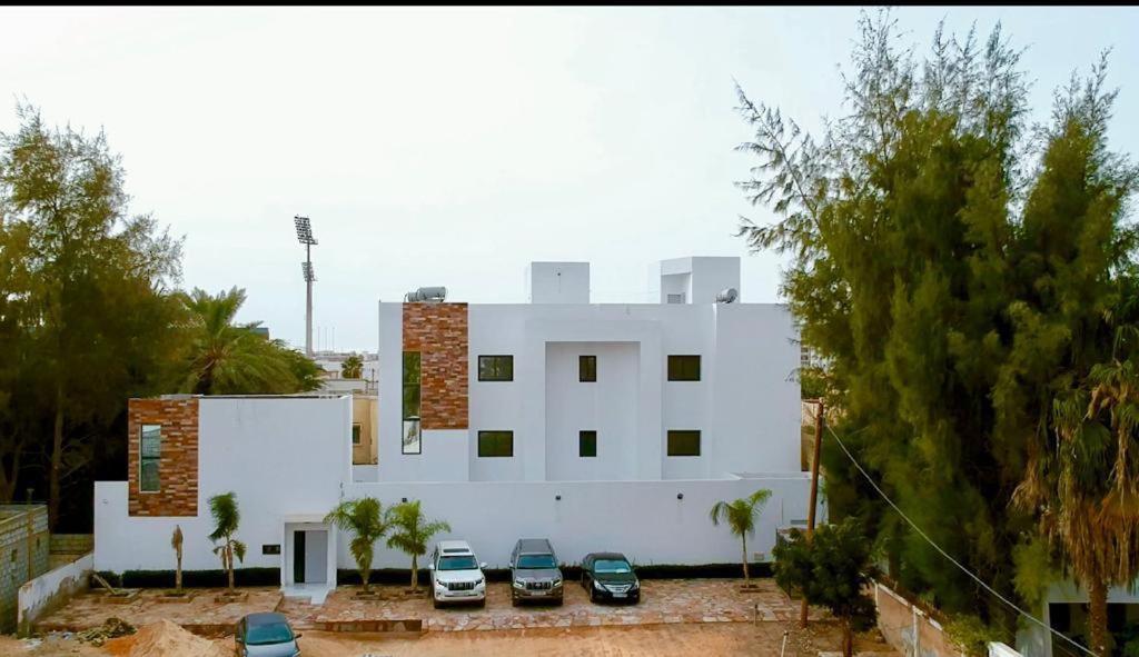 ein weißes Gebäude mit davor geparkt in der Unterkunft Garden Suites in Nouakchott