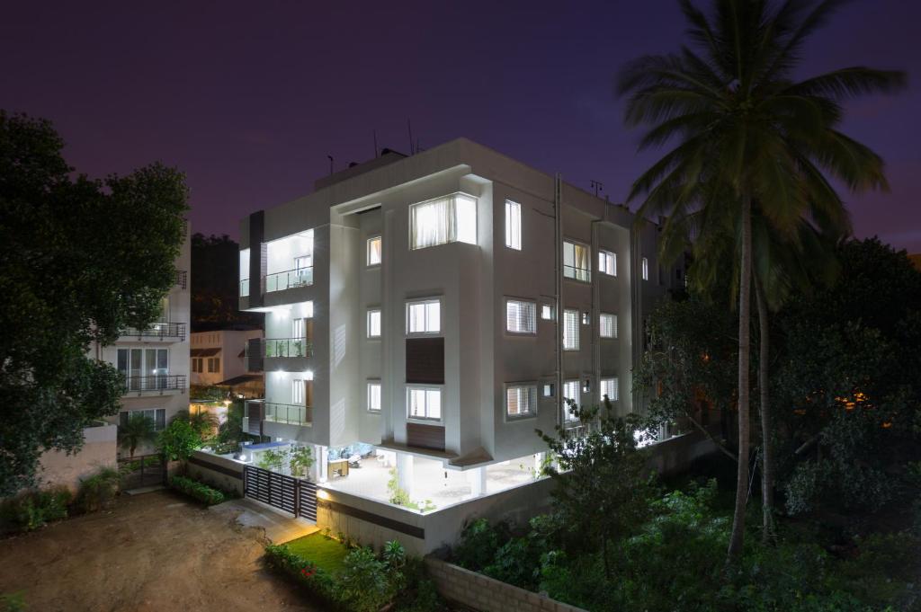 a large white building with a palm tree at night at Sanctum Suites BEL Road Bangalore in Bangalore