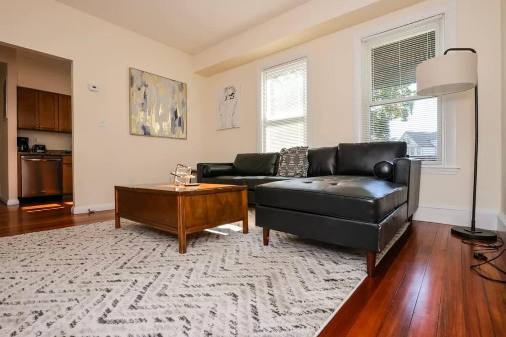 ein Wohnzimmer mit einem schwarzen Ledersofa und einem Couchtisch in der Unterkunft Stylish Apartment in Malden 20 Min from Boston #2 in Malden