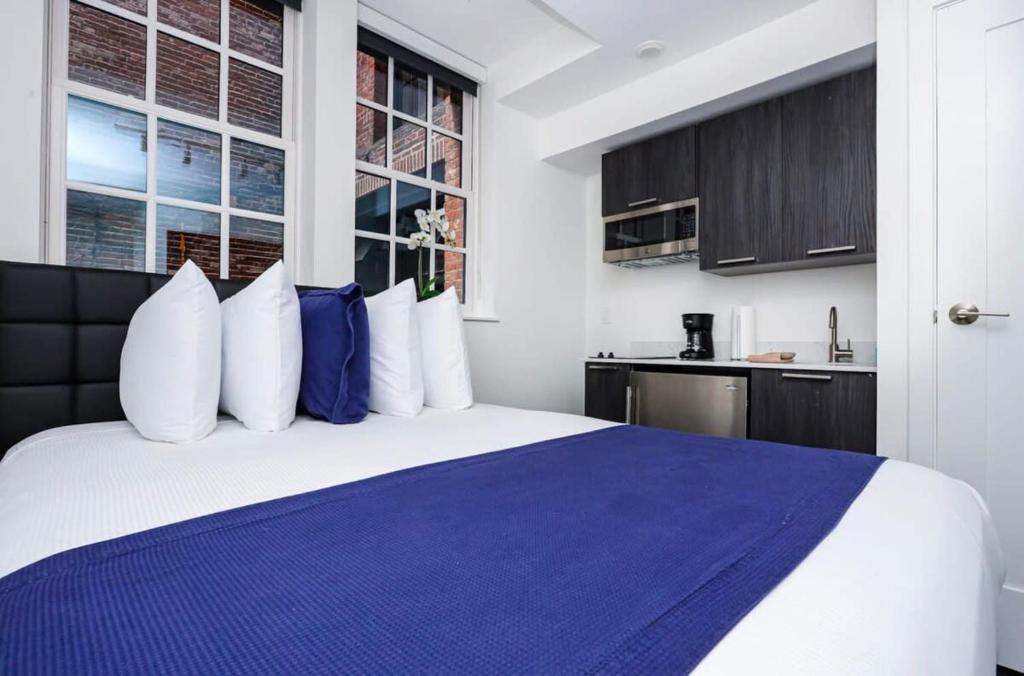 a bedroom with a large bed with blue and white pillows at Modern Studio in Historic Boston - Garden Unit #4 in Boston