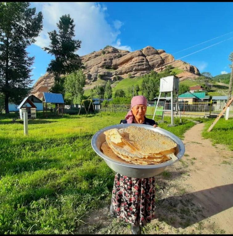 Een vrouw houdt een bakje brood vast. bij Aisun guest house in Kyzylunkyur