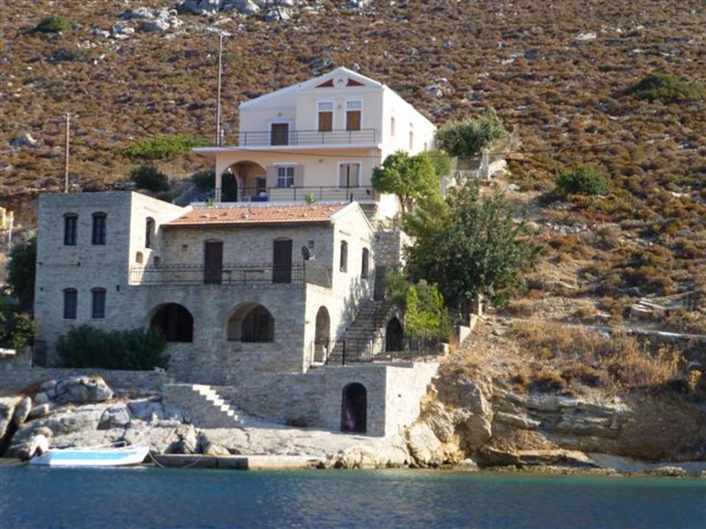 a house on the side of a hill next to the water at Nimporio View Villa in Symi