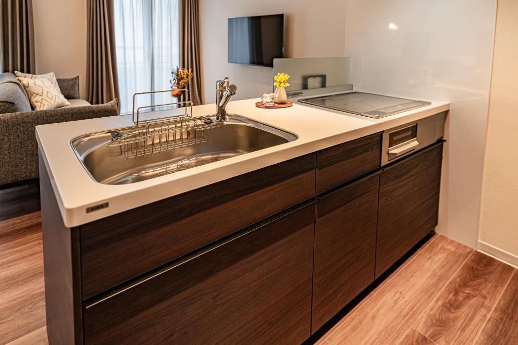 a kitchen with a sink and a living room at Apartment Hotel 11 Shinsaibashi AMEMURA in Osaka