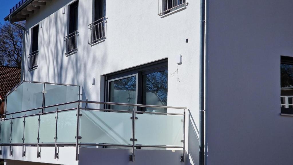 balcón de un edificio con barandilla de cristal en Ferienhaus Sisi - Moderner Neubau im Grünen, nahe See, S-Bahn und mit E-Ladesäule, en Pöcking