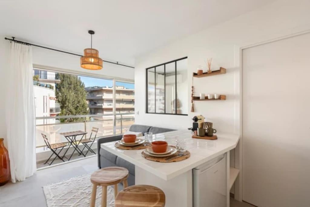 une cuisine avec un comptoir blanc et une grande fenêtre dans l'établissement Appartement Cannes 1 chambre - QG, à Cannes
