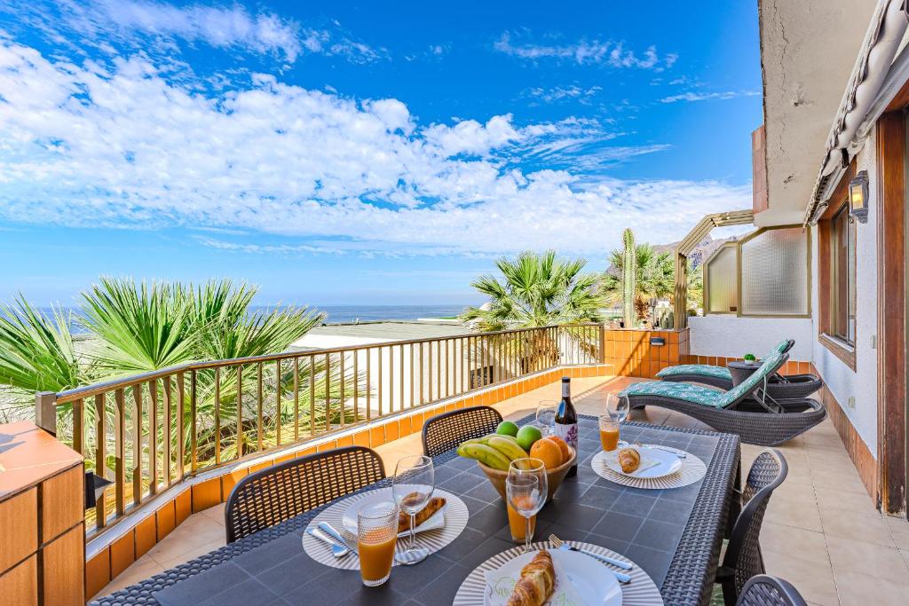 een patio met een tafel met eten en drinken op een balkon bij Great Apartment in Los Gigantes in Acantilado de los Gigantes