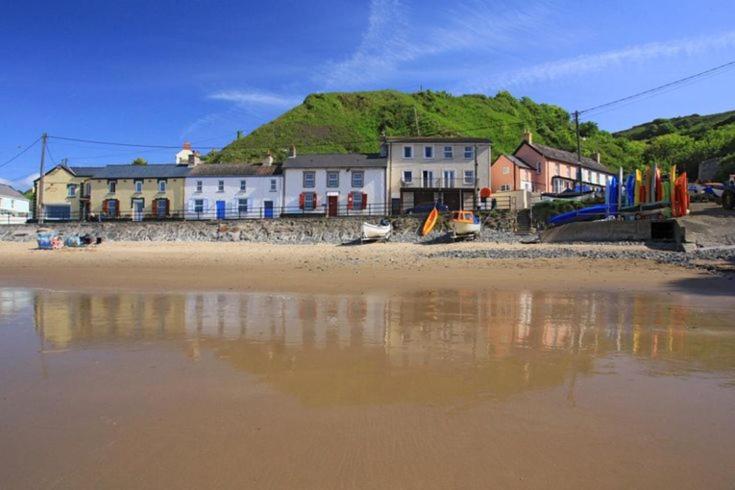 a beach with houses and reflections in the water at Aberafon Llangrannog in Llandysul