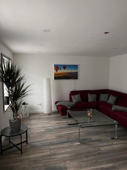 un soggiorno con divano rosso e tavolo di Haschys Ferienwohnung a Osterburg
