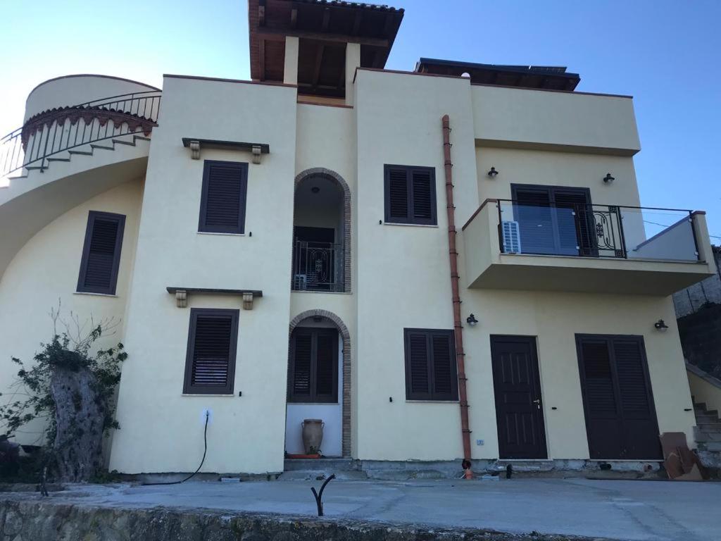 un edificio bianco con persiane nere e balcone di Villa San Leonardo a Santo Stefano di Camastra