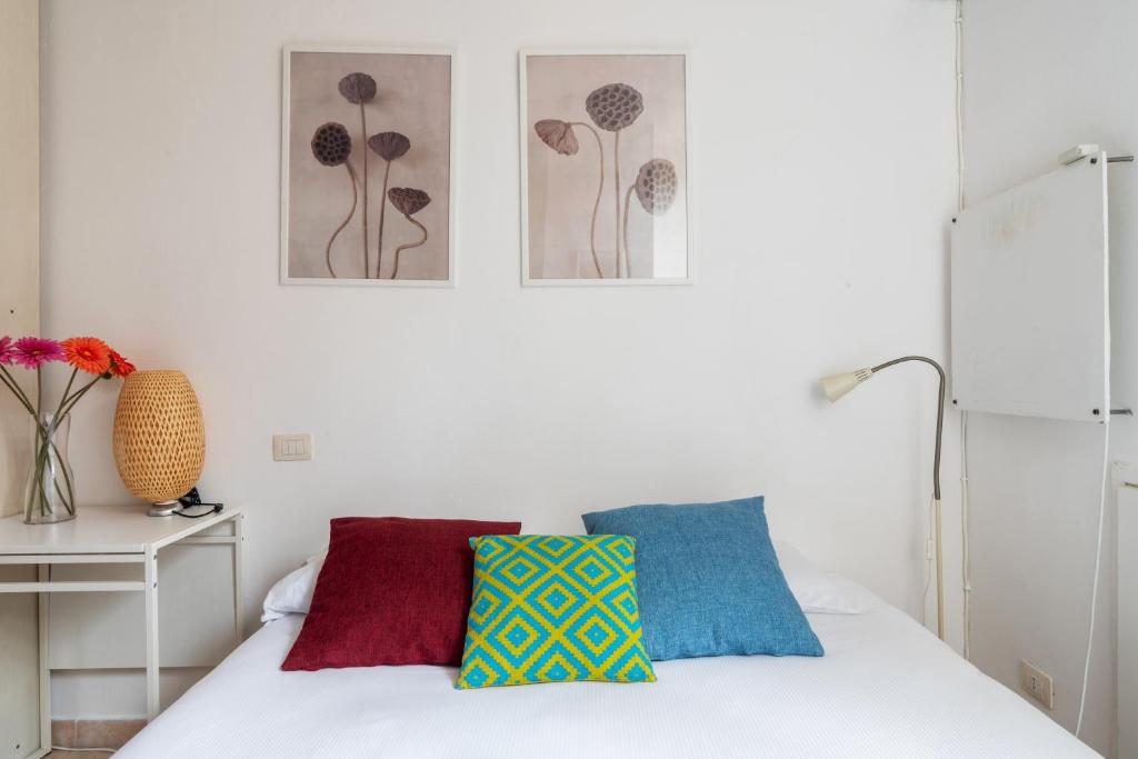 una camera da letto con un letto bianco con cuscini colorati di Monolocale Sarpi a Milano