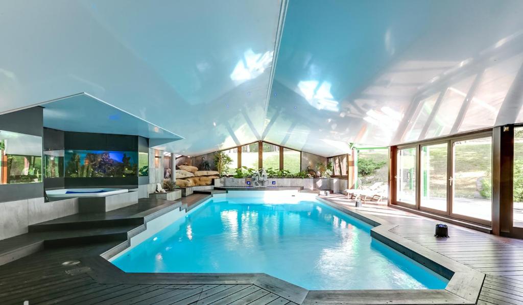 a swimming pool in a house with windows at Domaine de la Butte Ronde in La Boissière-École