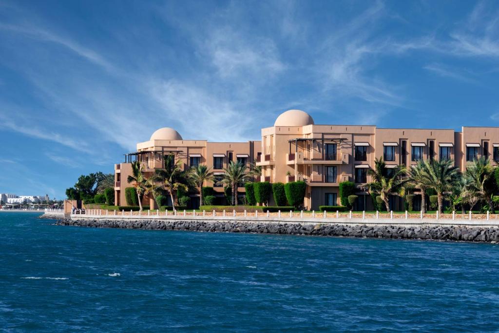 a building with palm trees in front of the water at Park Hyatt Jeddah - Marina, Club and Spa in Jeddah