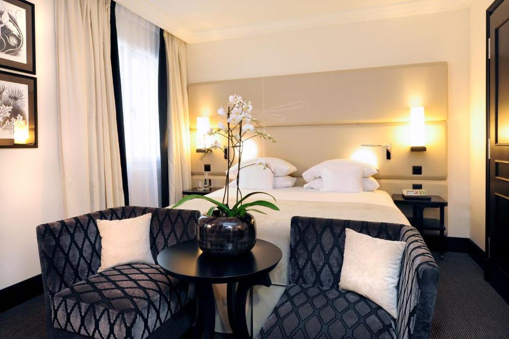 Habitación de hotel con cama, 2 sillas y mesa en Tiffany Hotel en Ginebra