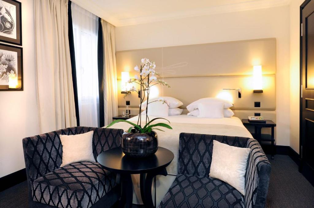 a hotel room with a bed and two chairs and a table at Hôtel Tiffany by Fassbind in Geneva