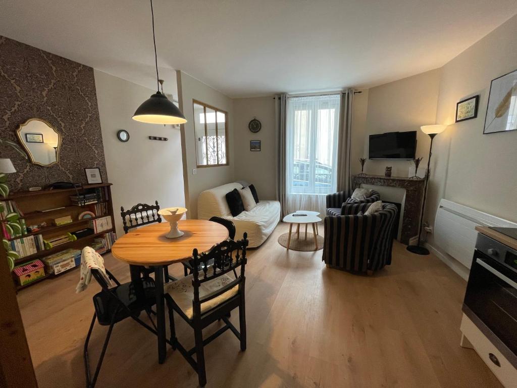 uma sala de estar com uma mesa e um sofá em Sisley Cottage em Moret-sur-Loing