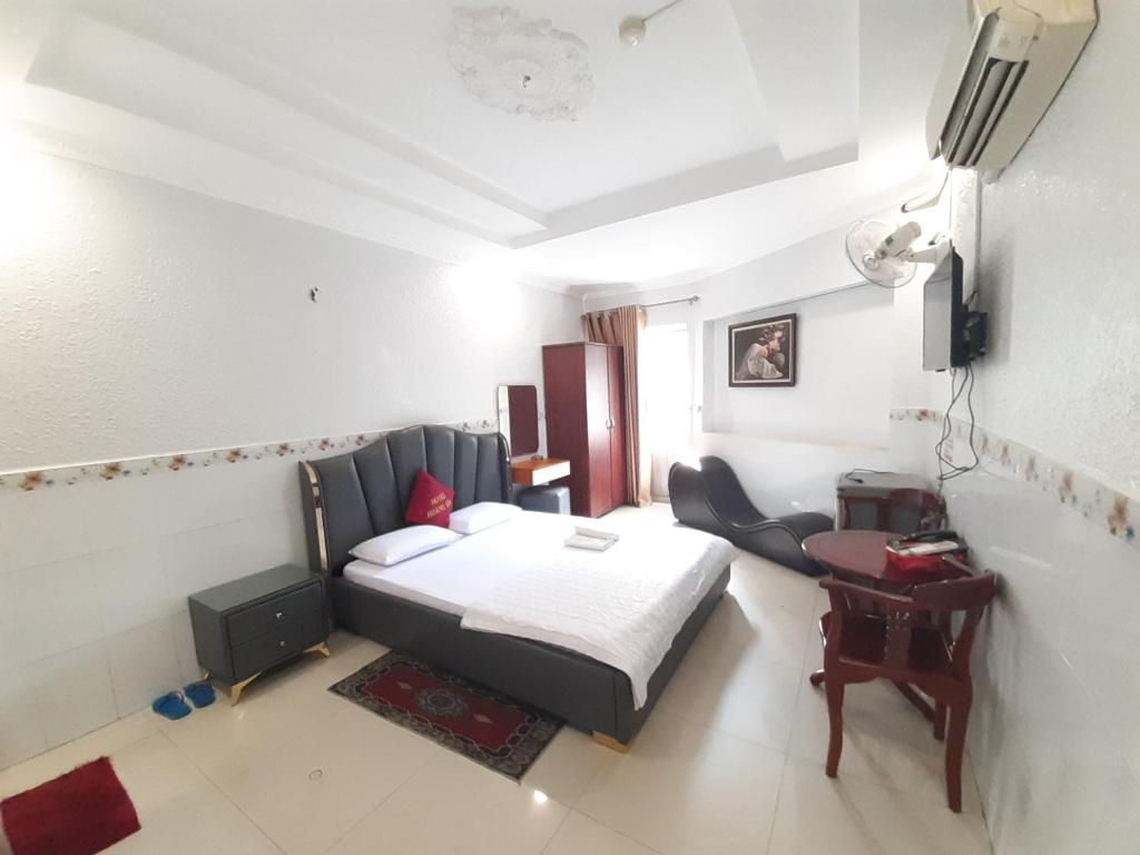 Schlafzimmer mit einem Bett, einem Schreibtisch und einem Stuhl in der Unterkunft OYO 1226 Hoang Gia Hotel in Ho-Chi-Minh-Stadt