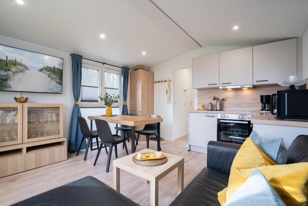 ein Wohnzimmer mit einem Sofa und einem Tisch in der Küche in der Unterkunft Ostseecamp Ferienhaus "Sonneneck" mit umzäuntem Grundstück in Scharbeutz