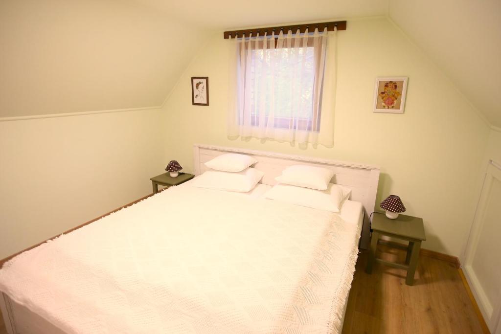 1 dormitorio con cama blanca y ventana en Góhér pince és vendégház, en Császártöltés