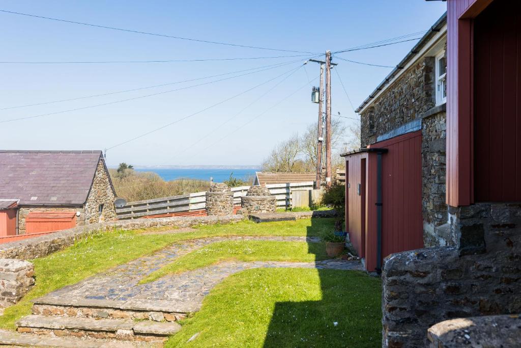 a stone house with a path leading to a building at Pine Cottage Little Haven in Little Haven