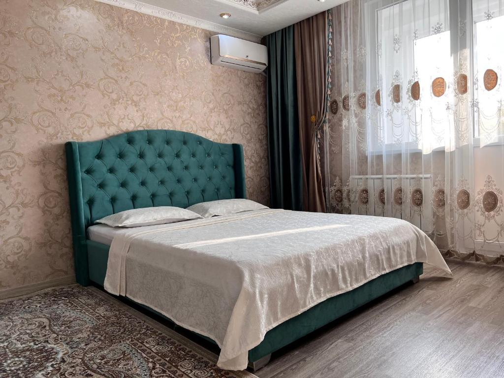 a bedroom with a bed with a green headboard and a window at ЖК Алмалы напротив Алматы Арены 47-6 in Almaty