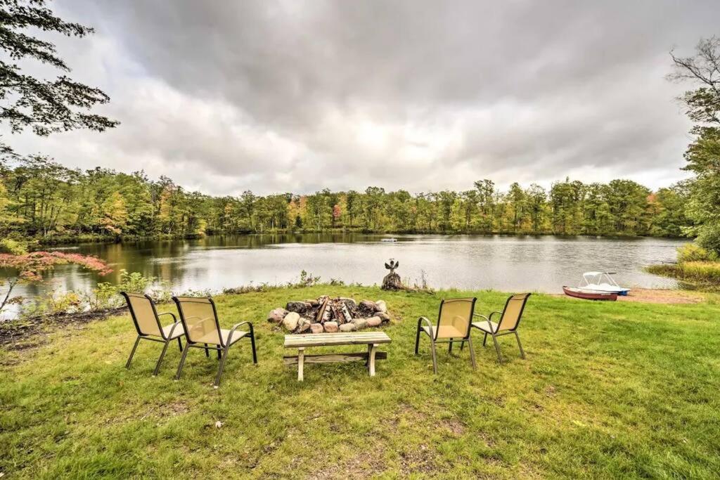 a group of chairs around a fire pit next to a lake at Tower Lake Vacation Home & Cabin in Birchwood