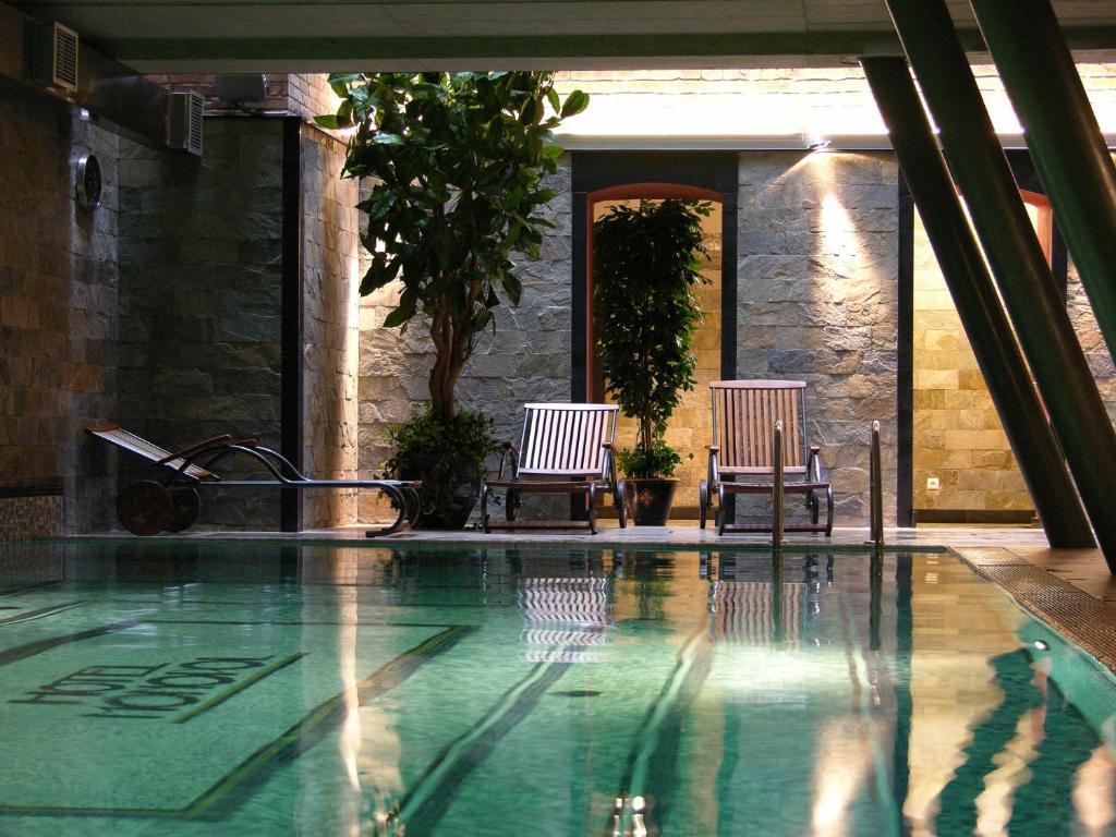 カトヴィツェにあるホテル モノポール カトーウィツェのスイミングプールの隣に椅子2脚
