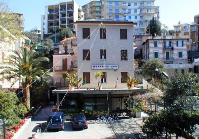 un grand bâtiment avec des voitures garées dans un parking dans l'établissement Hotel Villa Camilla, à Varazze