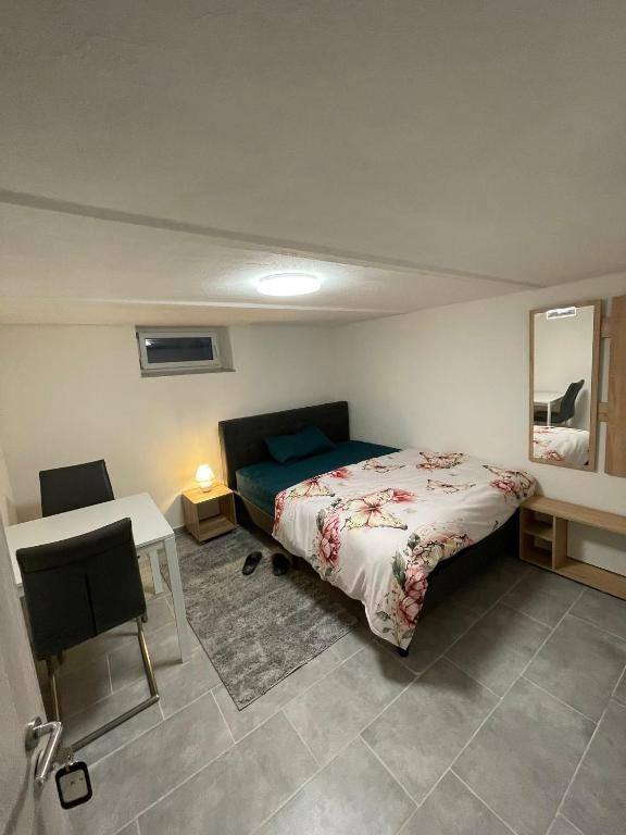 1 dormitorio con cama, mesa y espejo en gemütliches und Schönes Zimmer Keller Geschoss K1, en Haßloch