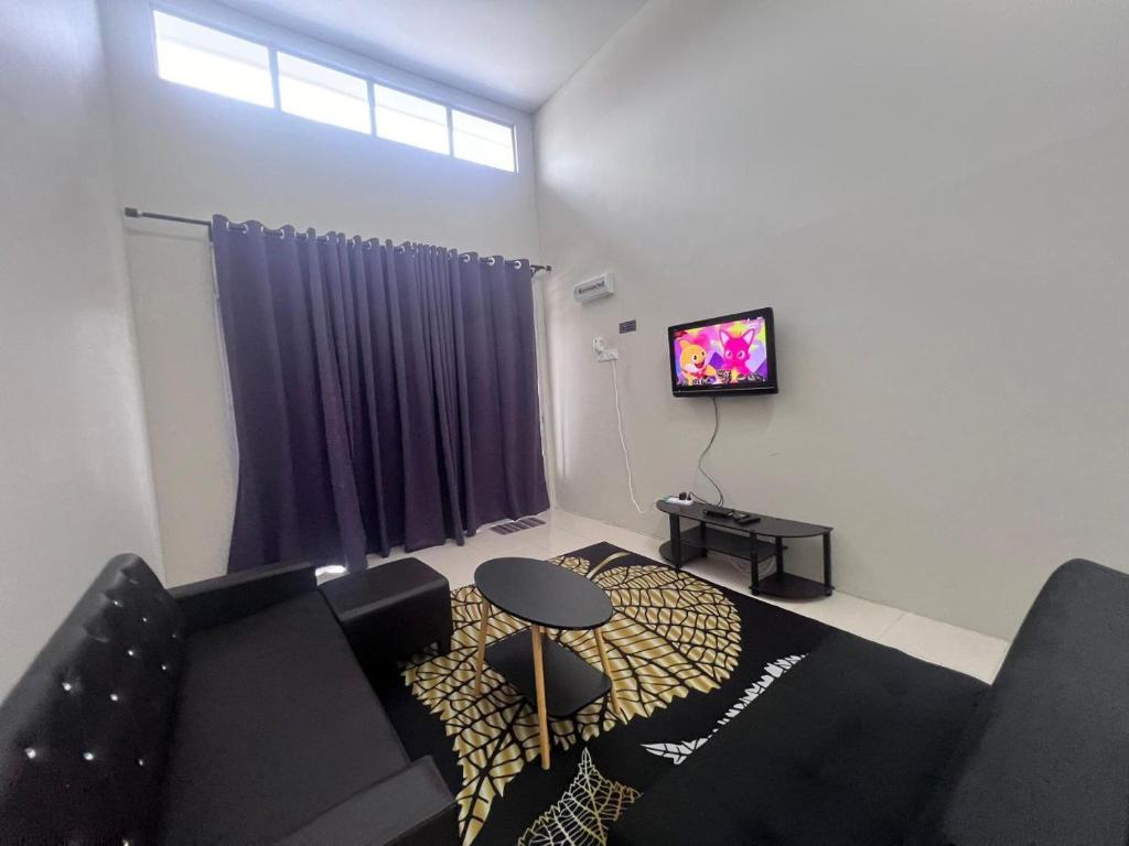 ein Wohnzimmer mit einem Sofa, einem Tisch und einem TV in der Unterkunft HOMESTAY DE’AMRIZ in KAPAR-MERU-KLANG-PUNCAK ALAM-SHAH ALAM in Kapar