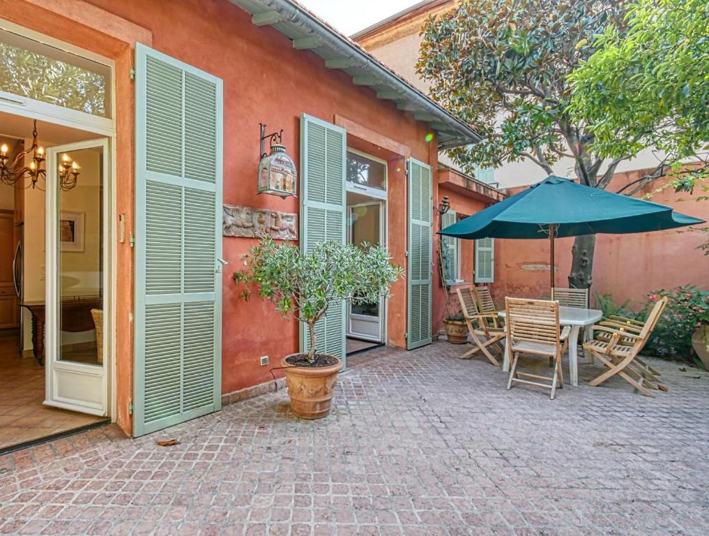un patio con mesa y sombrilla en Beautiful Air-Con House 5min from the Beaches, en Cannes