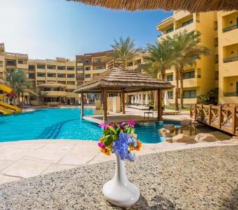 a vase filled with flowers sitting in front of a pool at Zahabia Hotel & Beach Resort in Hurghada