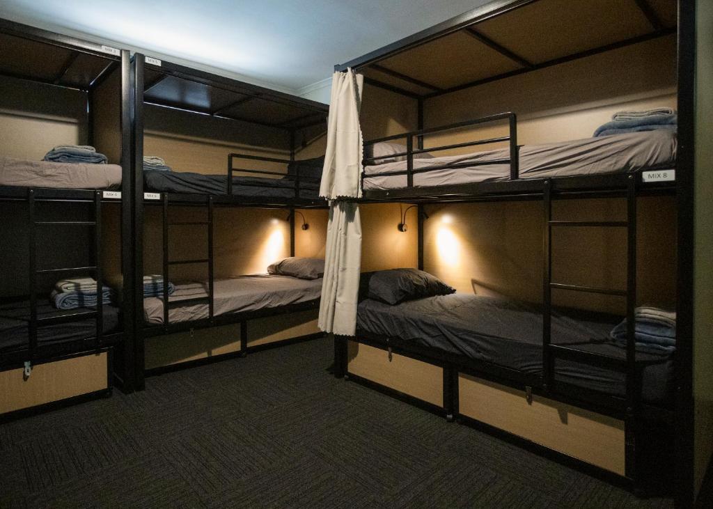 a room with three bunk beds in it at Base Camp Hostel in Adelaide
